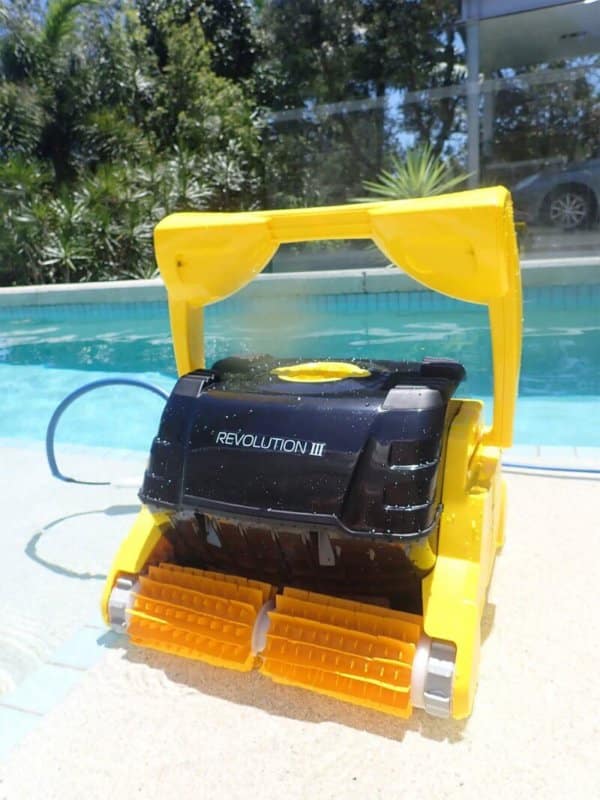 Revolution robotic pool cleaner next to swimming pool.